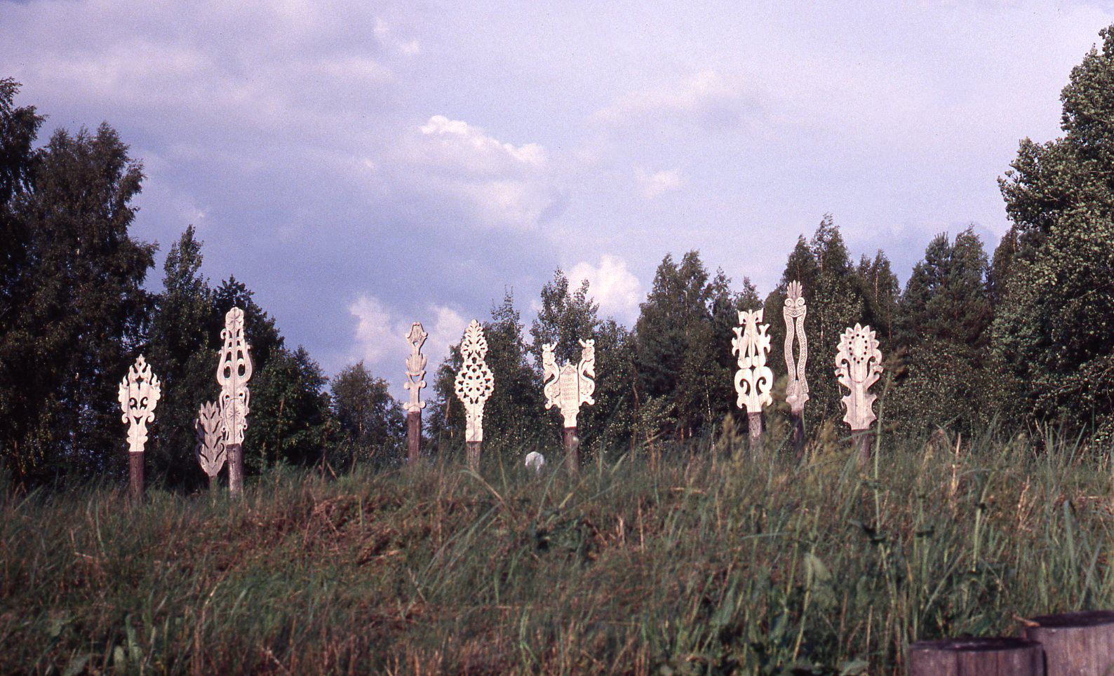 In 1976 fifteen carvers gathered in Usenai to install a memorial in honor of the Lithuanian army division who, in 1944, liberated the port city of Klaipeda occupied by the Germans. The 12 tall monuments, graceful in their curvilinear forms, were raised on a man-made mound, visible from the road. In contrast to the totem poles, these artifacts were cut out of thick boards and carved to resemble the ornamental distaff of a spinning wheel. The geometric patterns made these artifacts tolerable during Soviet occupation because they did not openly contravene Communist ideology. Because it was forbidden to make crosses and wayside shrines, artists turned to the “decorative and ideologically neutral distaff.” courtesy of Milda Richardson